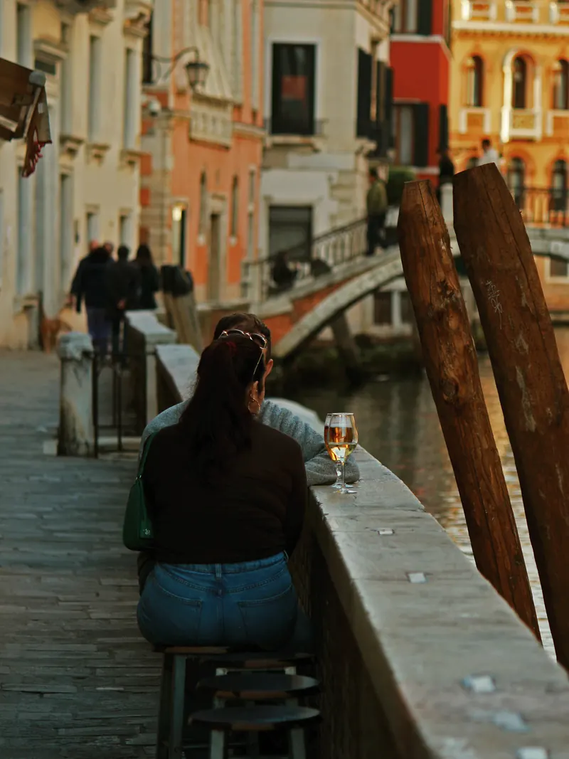 Mujer de espaldas apoyada en la barandilla de un canal.