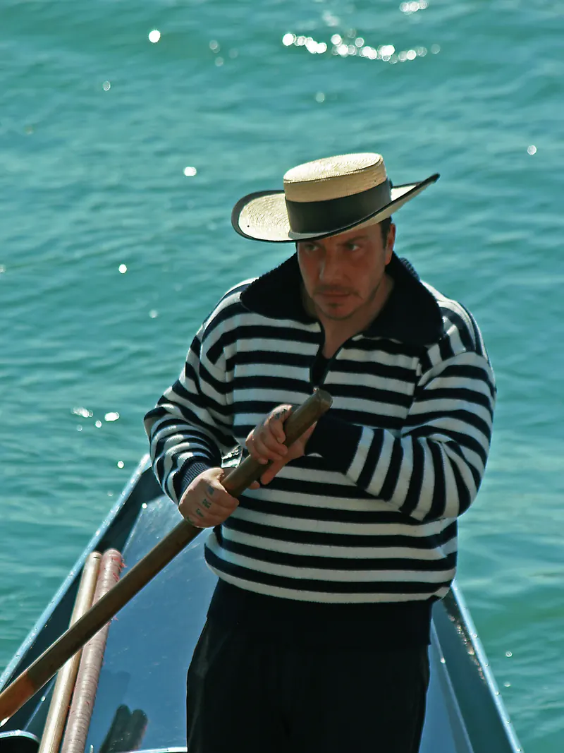 Gondolero con sombrero de paja remando de frente.