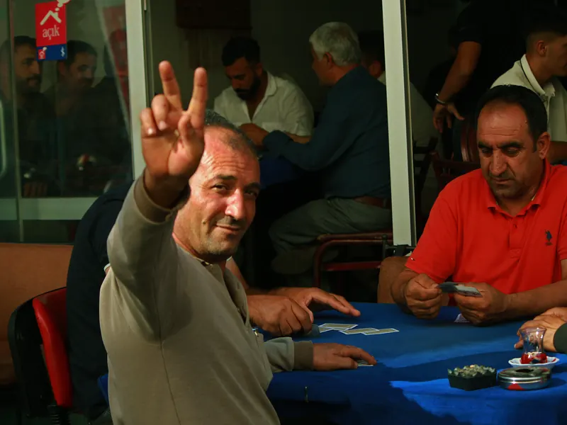 Hombre levantando la mano en señal de victoria en una partida de cartas.