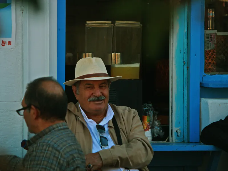 Dos hombres charlando en la puerta azul de un local.