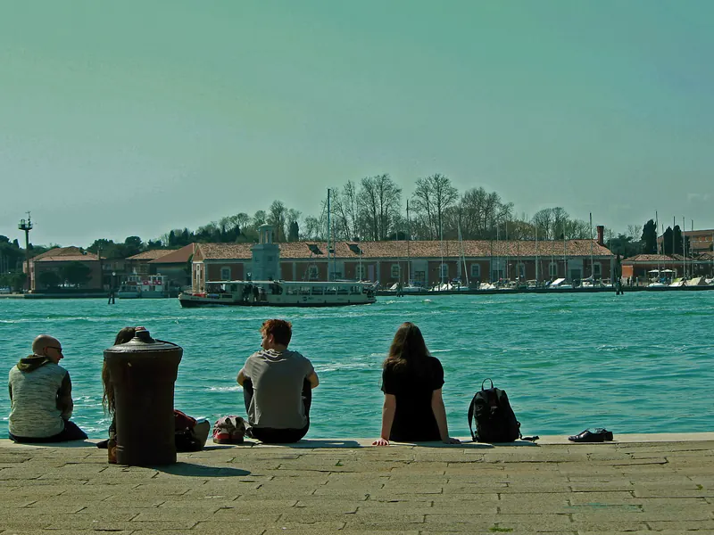 Grupo de amigos sentados mirando el agua desde el muelle.