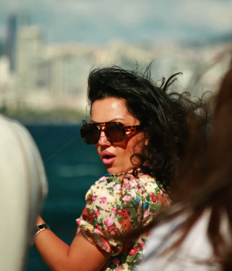Mujer con gafas de sol y el pelo al viento en un barco.