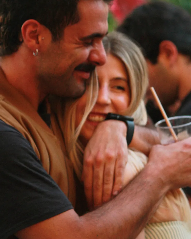 Una pareja abrazada entre risas en una fiesta.